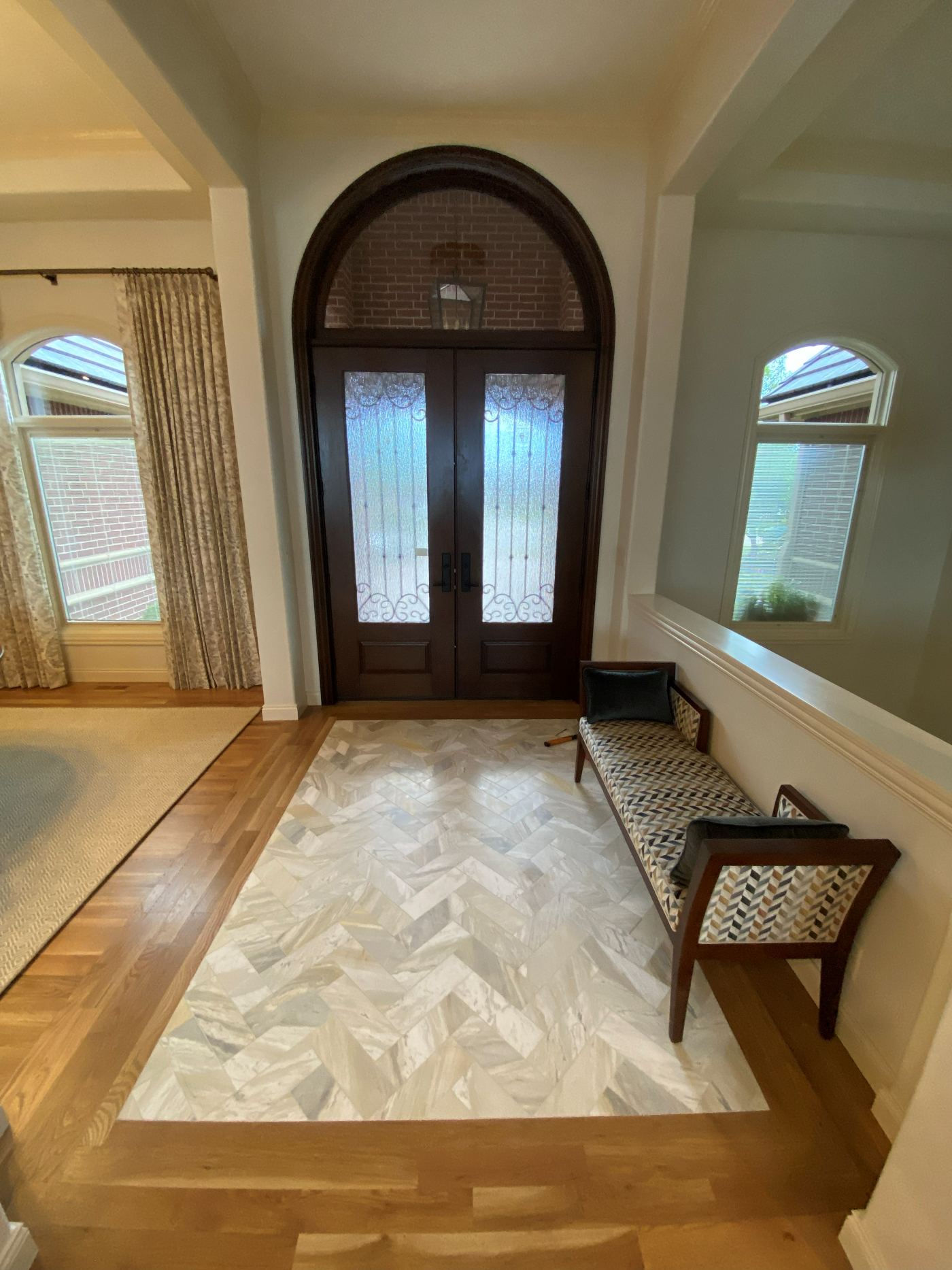 Marble herringbone tile entry inlay bordered by hardwood flooring